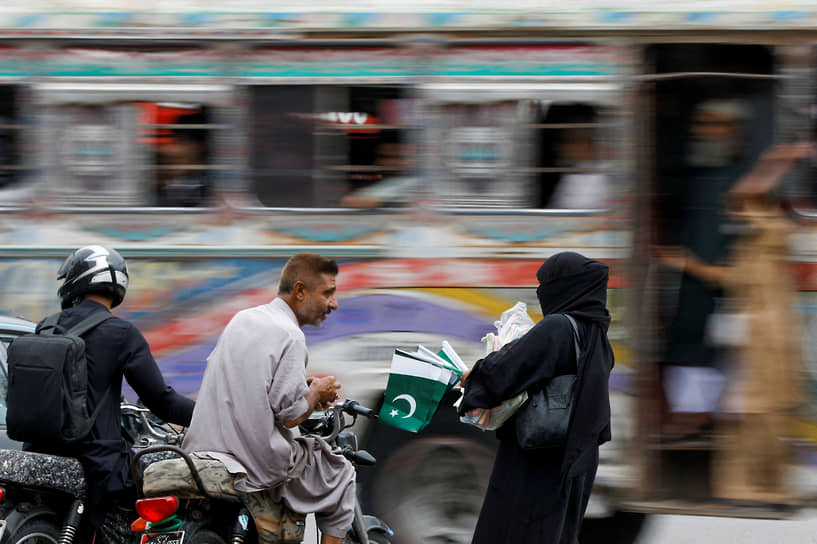 Карачи, Пакистан. Продавщица флагов с покупателем в преддверии дня независимости Пакистана