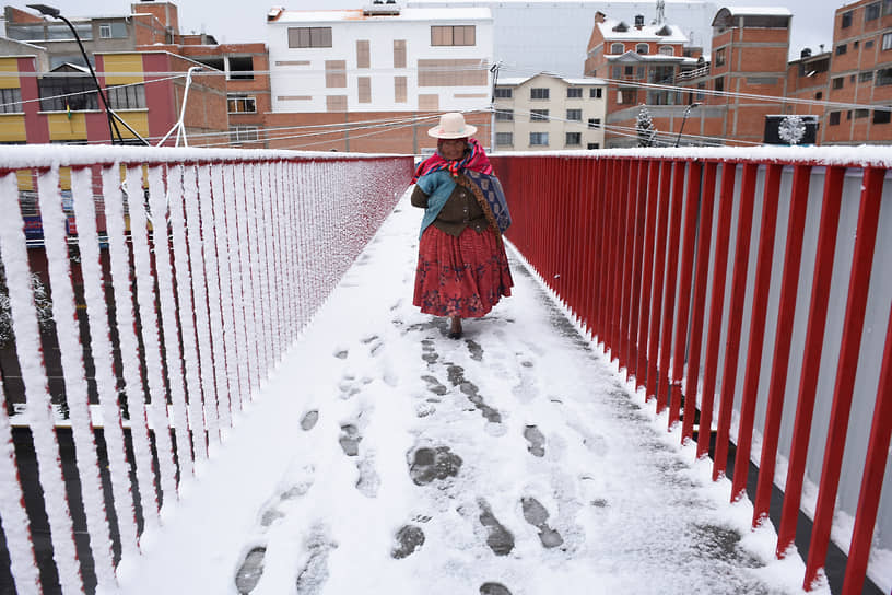 Эль-Альто, Боливия. Женщина переходит пешеходный мост после cнегопада 