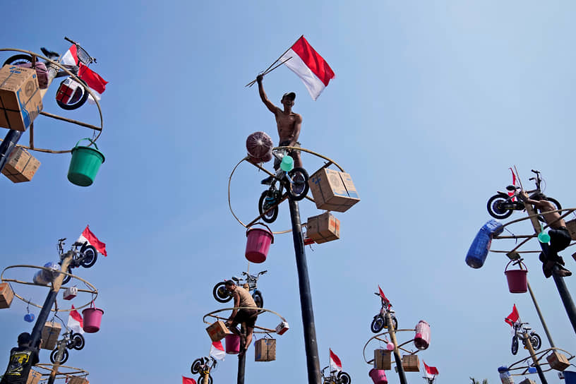 Джакарта, Индонезия. Участник соревнований в честь Дня независимости размахивает флагом страны на вершине столба