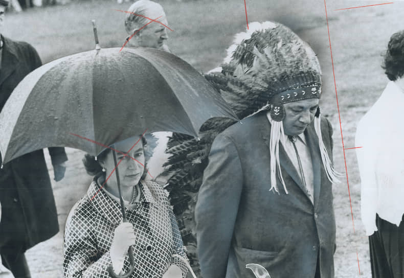 Вождь индейцев прогуливается с королевой Елизаветой II во время визита королевской семьи в резервацию в канадской провинции Манитоба, 1970 год