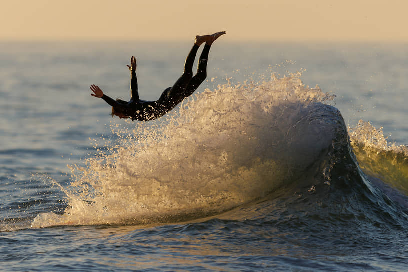Энсинитас, США. Серфер прыгает с гребня волны в воду