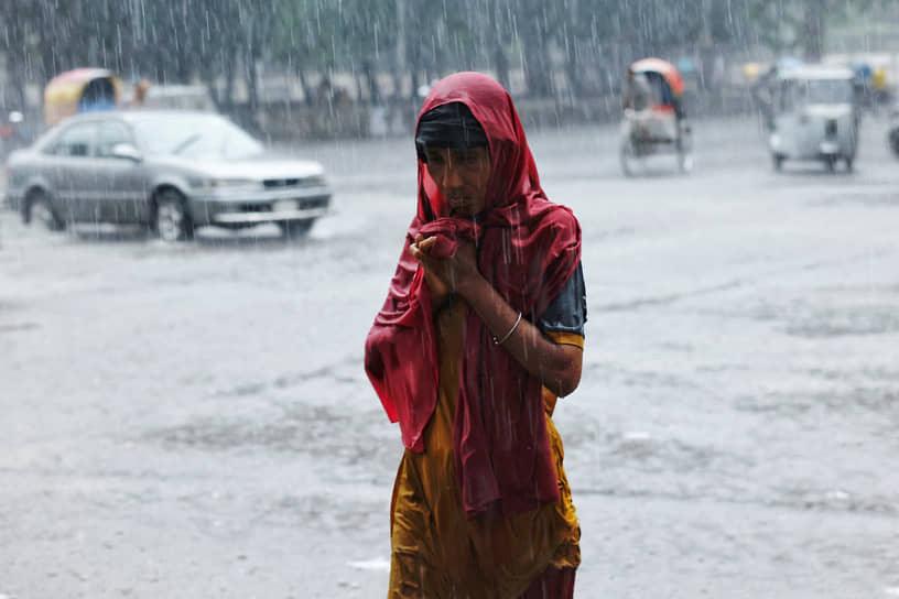 Дакка. Женщина идет по улице во время ливня