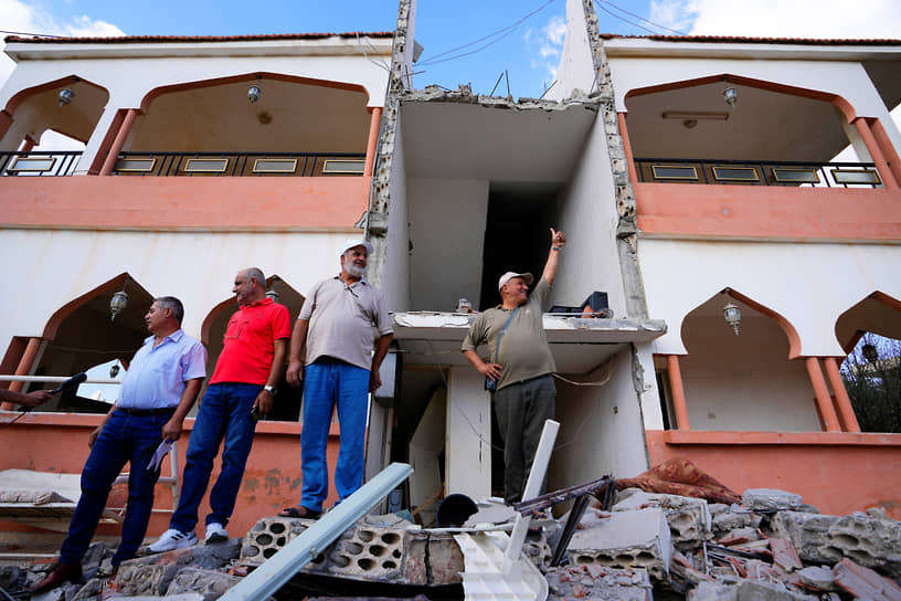 Ливанские мужчины осматривают дом, пострадавший от обстрела в приграничной деревне Духайр