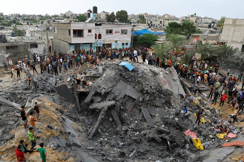 Палестинцы у разрушенного здания после ракетного удара Израиля 