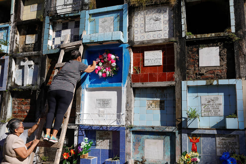Женщины возлагают цветы к местам упокоения своих родственников в Сан-Сальвадоре