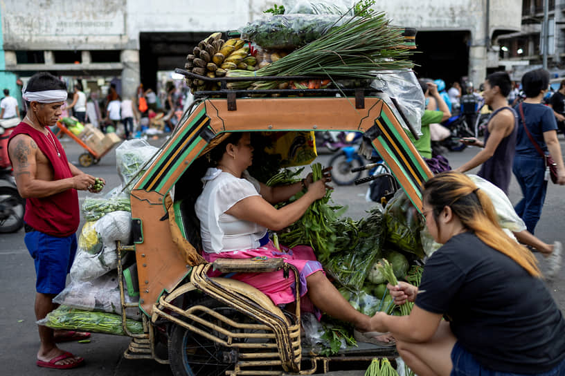 Манила Филиппины. Продавцы на рикше подготавливают овощи к продаже 