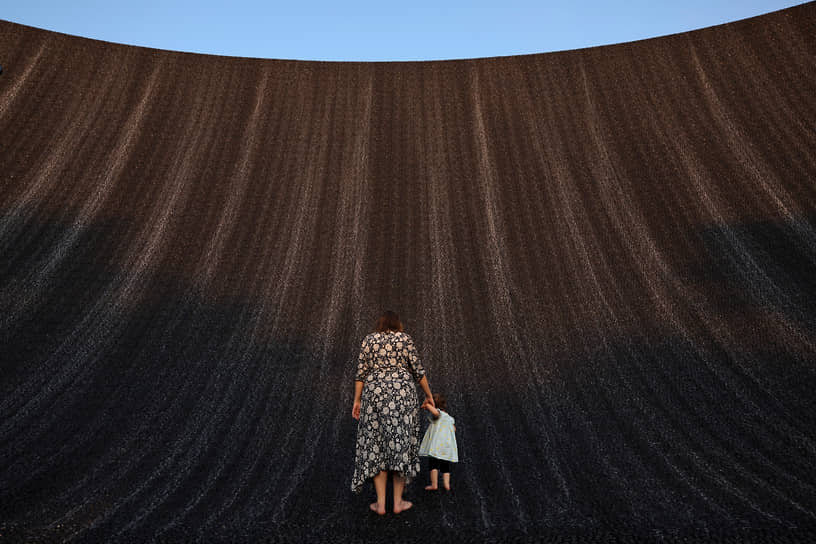Дубай, ОАЭ. Женщина с ребенком смотрит на водопад в выставочном центре Expo City Dubai, где проходит климатическая конференция ООН (COP28)