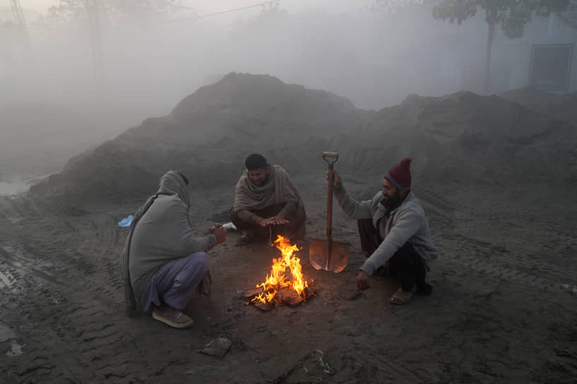 Лахор, Пакистан. Рабочие греются у костра во время тумана
