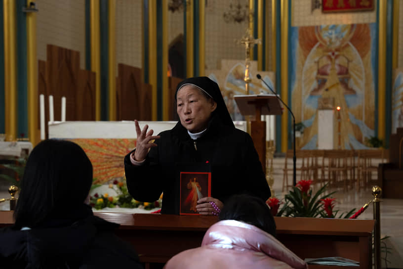 Пекин, Китай. Служительница церкви Сишику беседует с прихожанами перед мессой