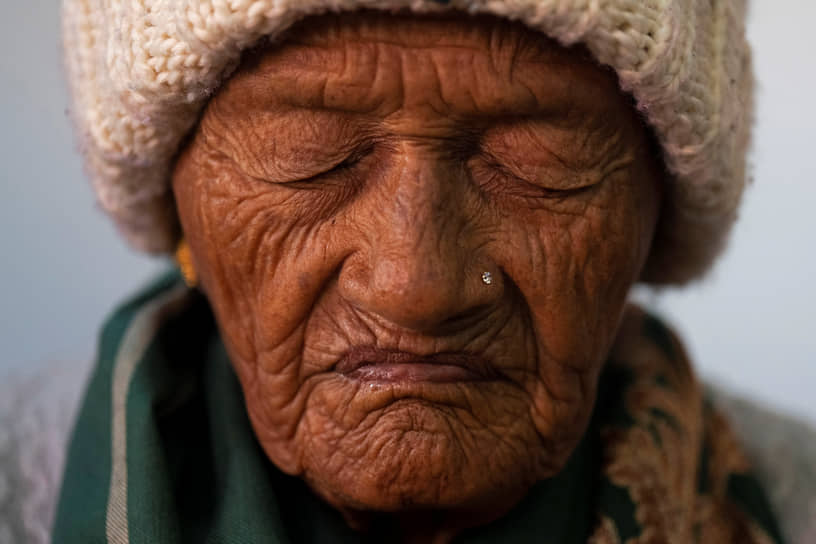 Катманду, Непал. Пожилая женщина читает молитву 