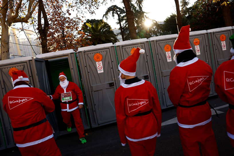 Мадрид, Испания. Люди в костюмах Санта-Клауса ждут возможности воспользоваться переносными туалетами перед началом благотворительного забега