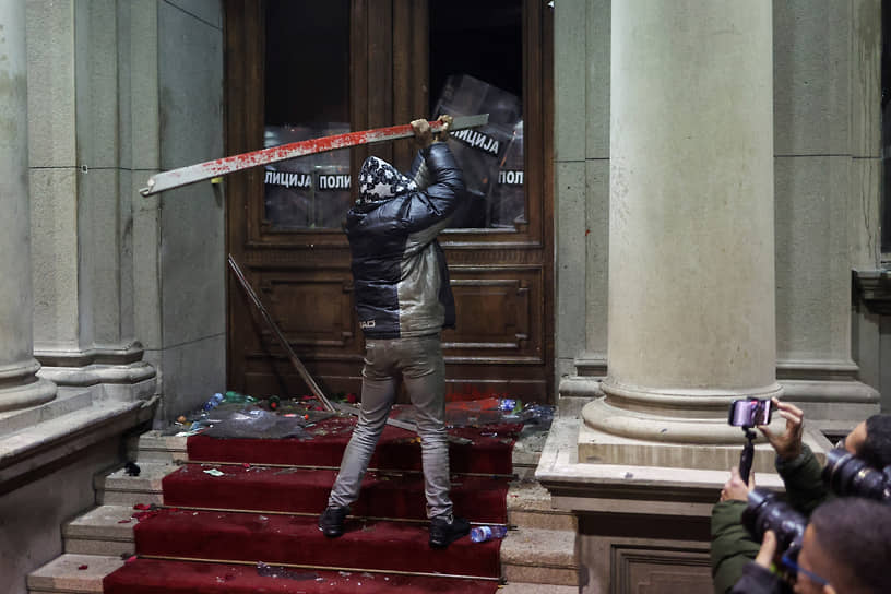 Белград, Сербия. Сторонник оппозиции атакует здание городской администрации, где находится Республиканская избирательная комиссия, в знак протеста против итогов выборов 
