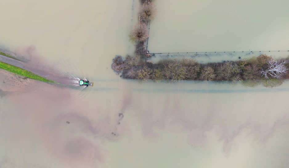 Трактор едет между затопленными полями в Хеммингене