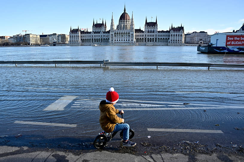 Ребенок едет на велосипеде по затопленной дороге в Будапеште