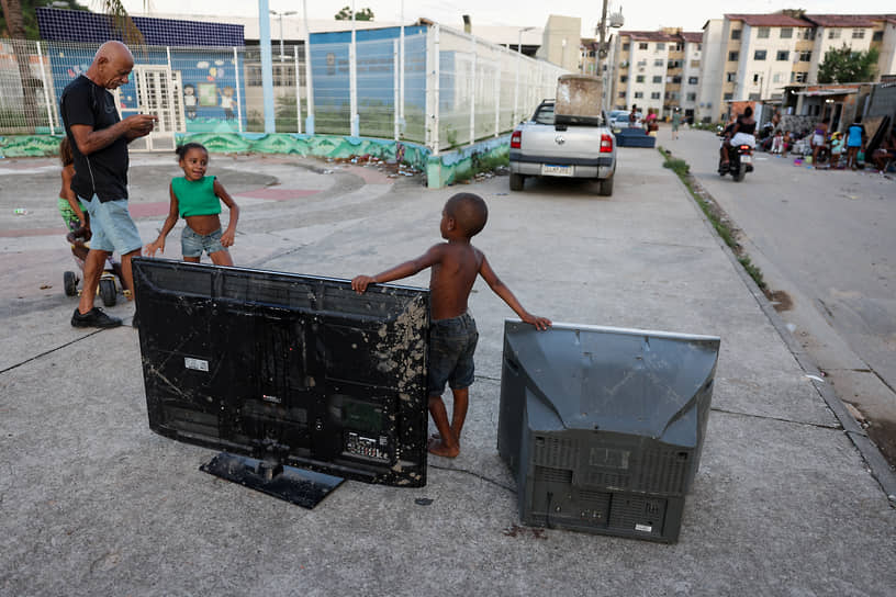 Рио-де-Жанейро, Бразилия. Ребенок из трущоб стоит рядом с телевизорами 
