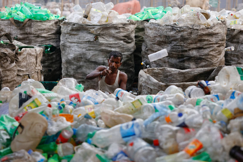 Дакка, Бангладеш. Рабочий завода по переработке пластмасс  снимает этикетки с бутылок 