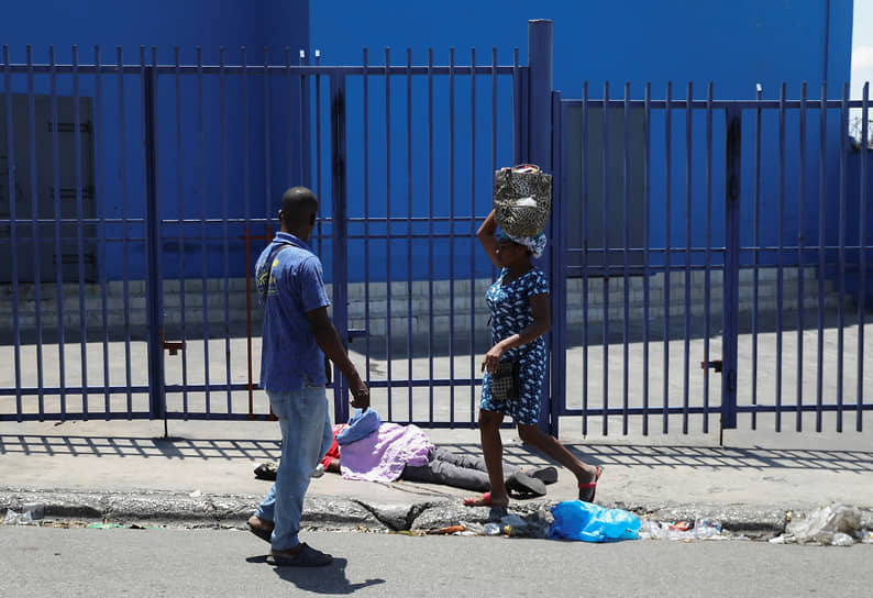 Местные жители продолжают заниматься повседневными делами несмотря на то, что тела погибших остаются на улицах &lt;br> На фото: тело погибшего во время беспорядков в Порт-о-Пренсе, апрель 2024 года