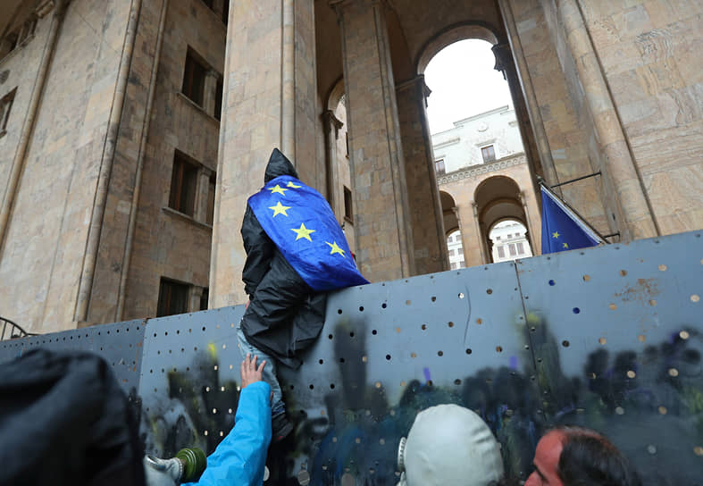 Протестующий сидит на заборе около парламента Грузии