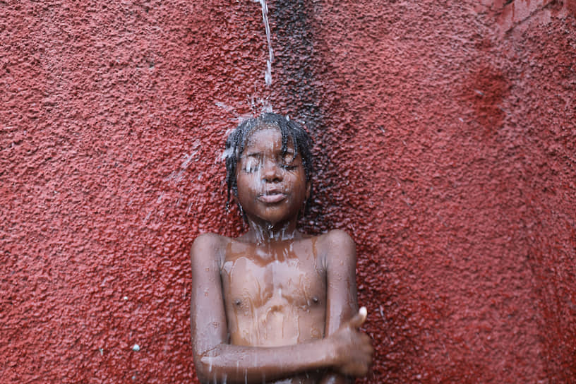 Порт-о-Пренс, Гаити. Мальчик принимает душ в Национальной школе имени Жозефа Бернара де Фрера, где он и другие дети укрываются от местных криминальных банд 
