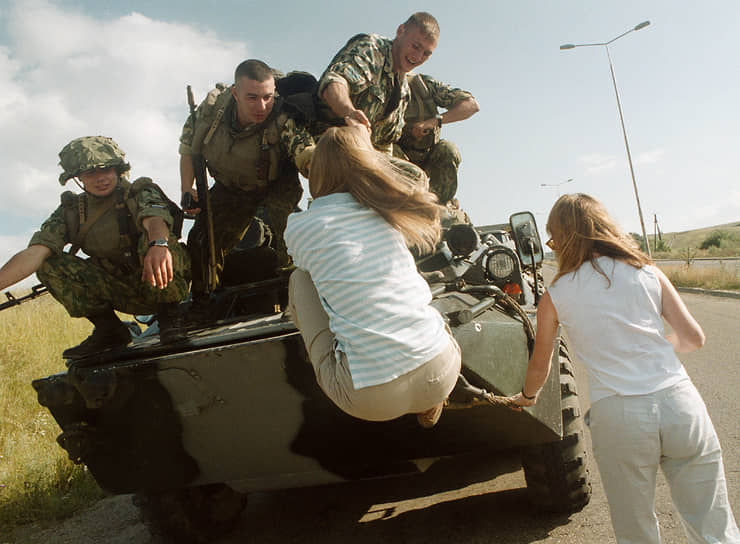 Солдаты российских миротворческих сил в Косово помогают сербским девушкам забраться на бронетранспортер
