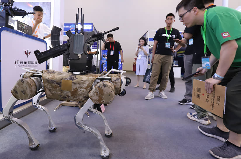 Посетители выставки передовых военных технологий в Пекине перед боевым робопсом китайского производства