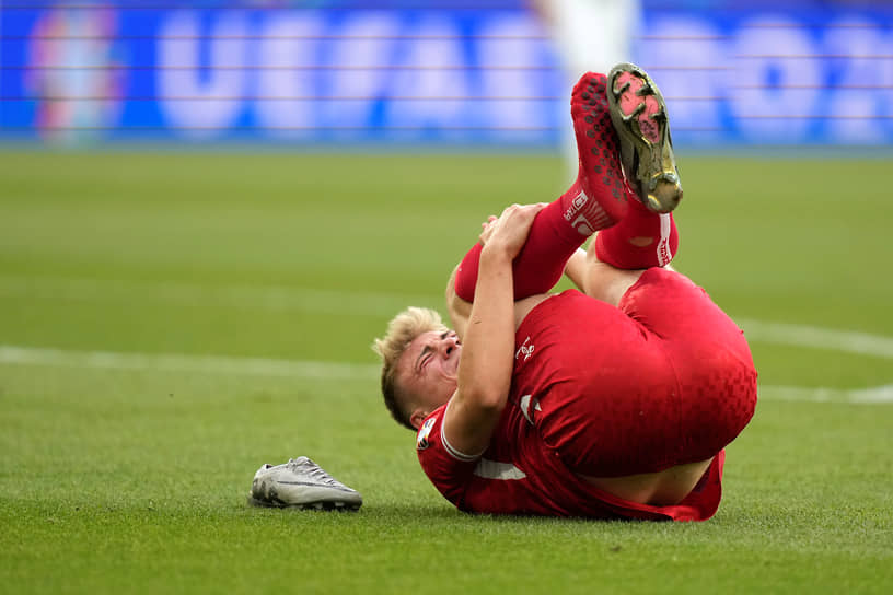 Датский нападающий Расмус Хёйлунн лежит на поле без бутсы во время матча против сборной Словении