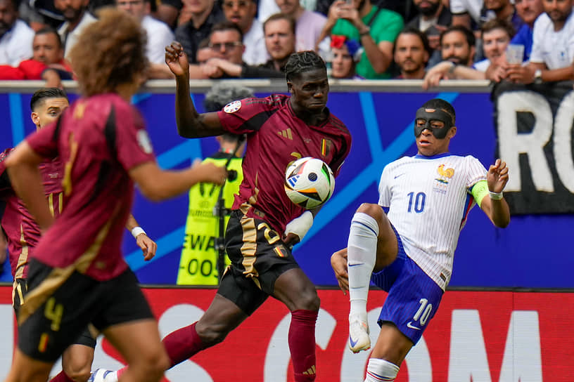 Бельгийский полузащитник Амаду Онана пытается помешать капитану и нападающему сборной Франции Килиану Мбаппе (справа) обработать мяч