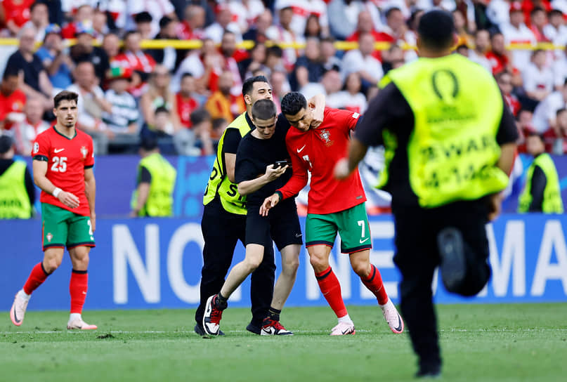 Болельщик, выбежавший на поле, обнимает нападающего сборной Португалии Криштиану Рональду 
