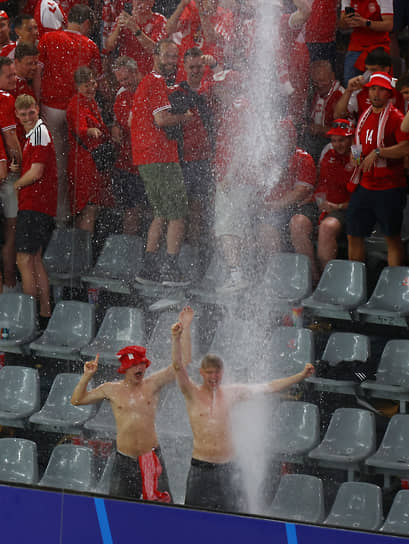Датские фанаты танцуют на трибуне под дождем, из-за которого был приостановлен матч против сборной Германии