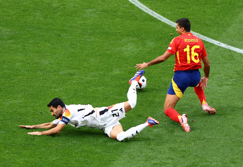 Капитан сборной Германии Илкай Гундоган борется за мяч с испанским полузащитником Родри