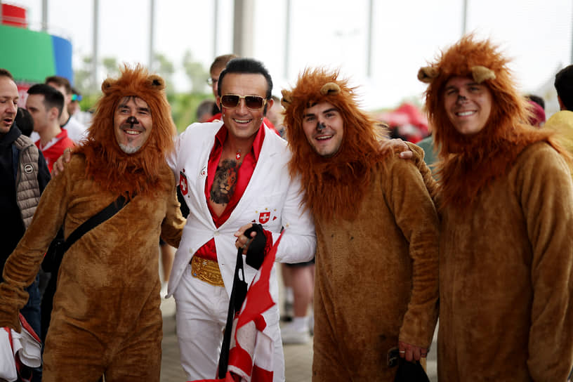 Болельщик из Швейцарии фотографируется с английскими фанатами в костюмах львов перед началом матча 