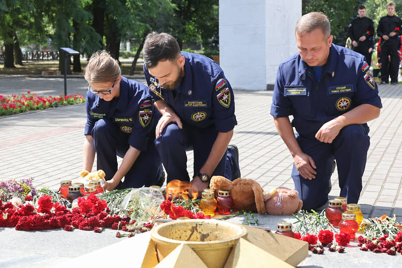 Сотрудники Всероссийского студенческого корпуса спасателей оставляют игрушки и цветы у мемориального комплекса «Братское кладбище» в Мелитополе 