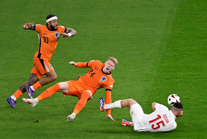 Турецкий футболист Салих Озджан борется за мяч с голландскими игроками Йерди Схаутеном и Мемфисом Депайем