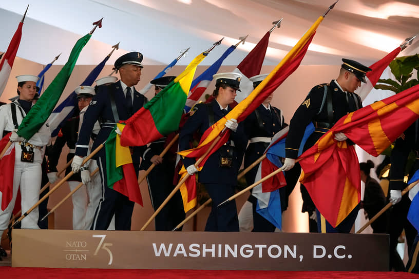 Военнослужащие выставляют флаги стран—участниц НАТО перед началом саммита