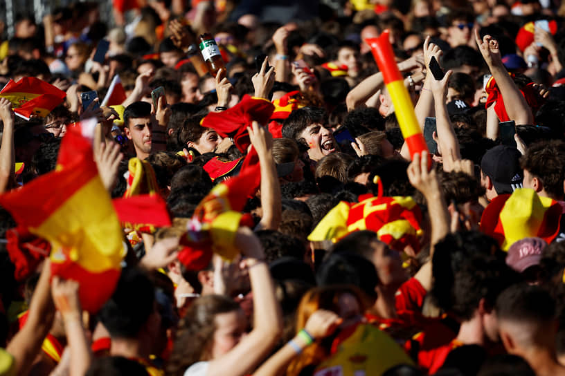 Десятки тысяч людей, одетые в красно-желтые цвета Испании, размахивают флагами 