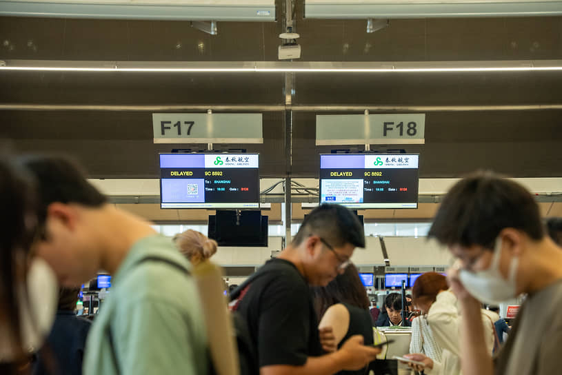 Пассажиры в аэропорту Бангкока Суварнабхуми стоят перед стойками регистрации, которые сообщают о задержках рейсов