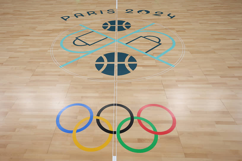 Олимпийские кольца, баскетбольная пиктограмма и надпись «Париж 2024», нанесенные на пол на стадионе «Пьер Моруа»