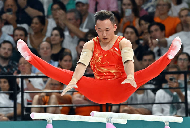 Китайский гимнаст Сяо Жотэн на брусьях во время соревнований по спортивной гимнастике