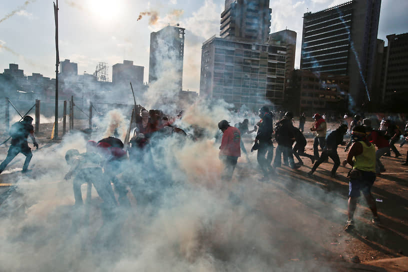Протестующие убегают после распыления силовиками слезоточивого газа в 2014 году