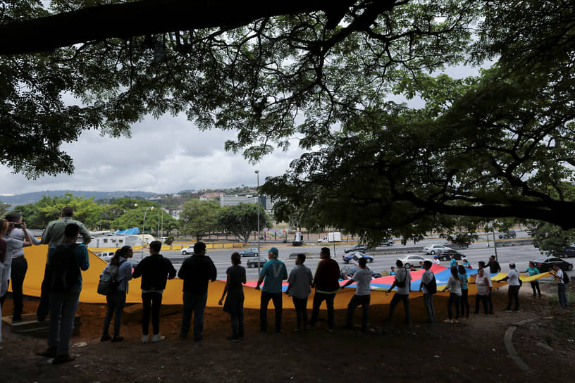 Люди держат флаг Венесуэлы на протестах, возникших после победы Николаса Мадуро на президентских выборах в 2018 году