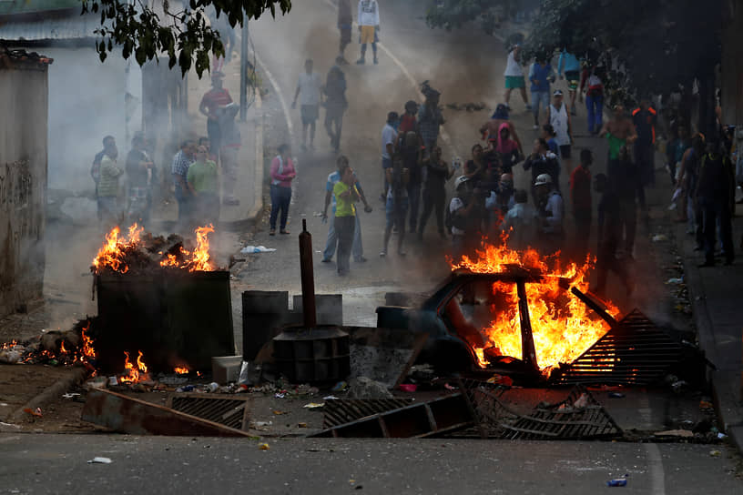 Горящие баррикады и демонстранты на протестах в Каракасе в 2019 году