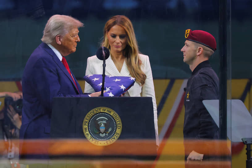 Президент Дональд Трамп (на фото слева) получает американский флаг от члена парашютной команды армии США «Золотые рыцари»