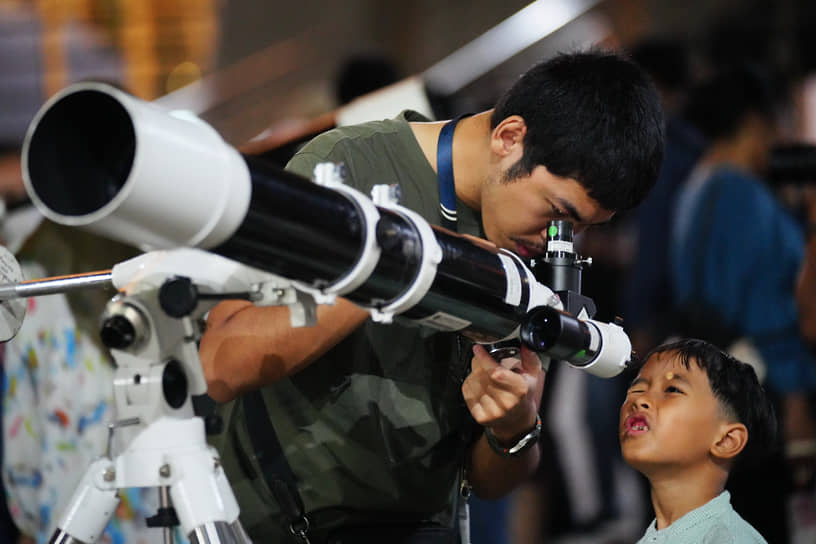 Мужчина использует телескоп для наблюдения за суперлунием в Джакарте, Индонезия