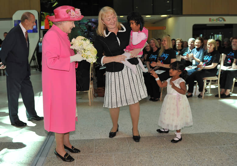 Королева Великобритании Елизавета II встречается с разделенными близнецами Клишной (слева) и Тришной и их матерью Майорой Келли, 2011