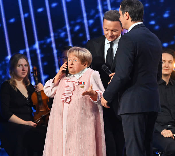 Президент РФ Владимир Путин по телефону поздравляет композитора Александру Пахмутову с днем рождения во время концерта
&lt;BR>На фото: композитор Александра Пахмутова и актер Александр Олешко (в центре)