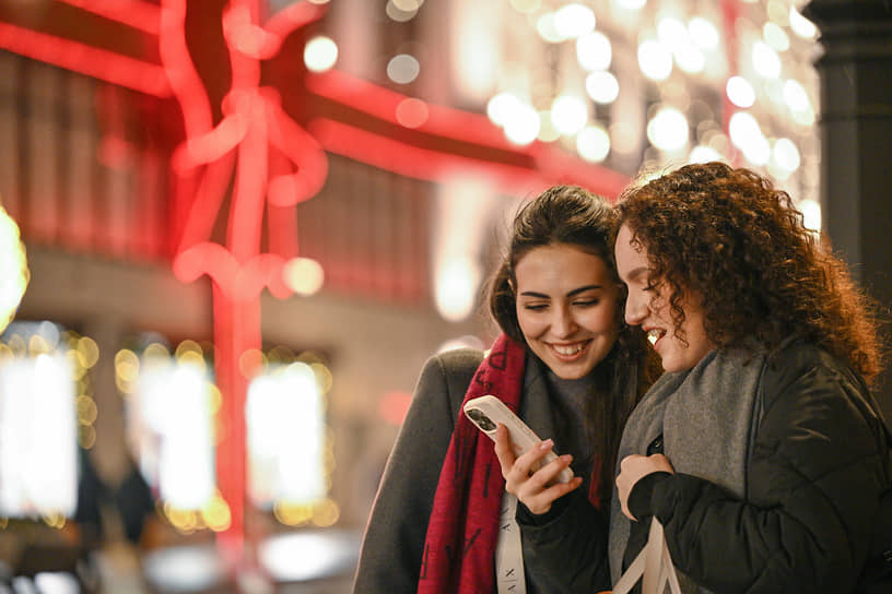 Девушки на фоне украшенного здания Центрального универсального магазина