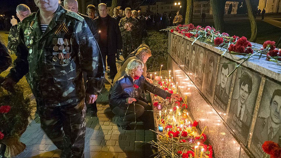 Люди зажигают свечи у мемориала, посвященного пожарным и работникам, которые погибли после аварии на Чернобыльской АЭС