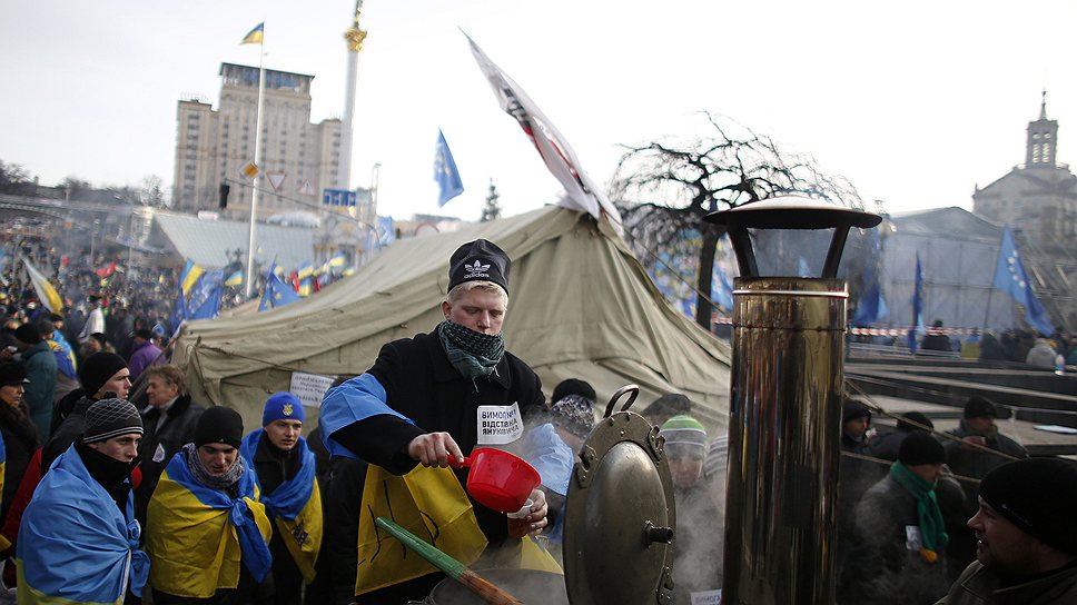 Человек, завернутый в украинский флаг раздает чай протестующим на майдане Незалежности