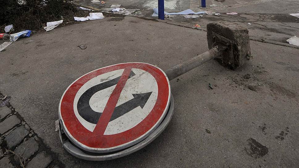 Дорожный знак лежит возле сгоревшего правительственного здания в городе Тузла