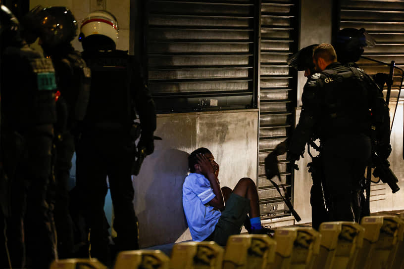 Полицейские и молодой человек — участник беспорядков в Париже